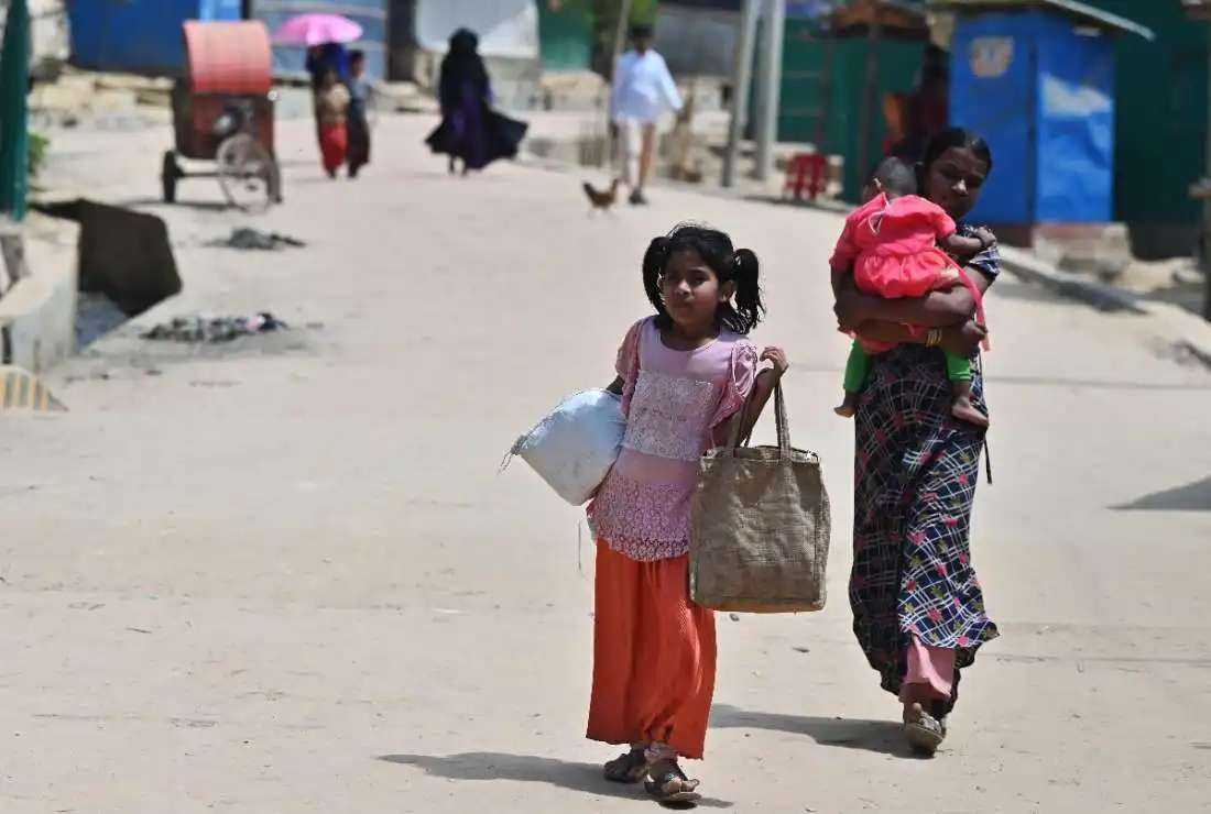 Rohingya people walk along a street after collecting relief materials in Jamtoli refugee camp in Ukhia, Cox's Bazar, Bangladesh, on March 22, 2022