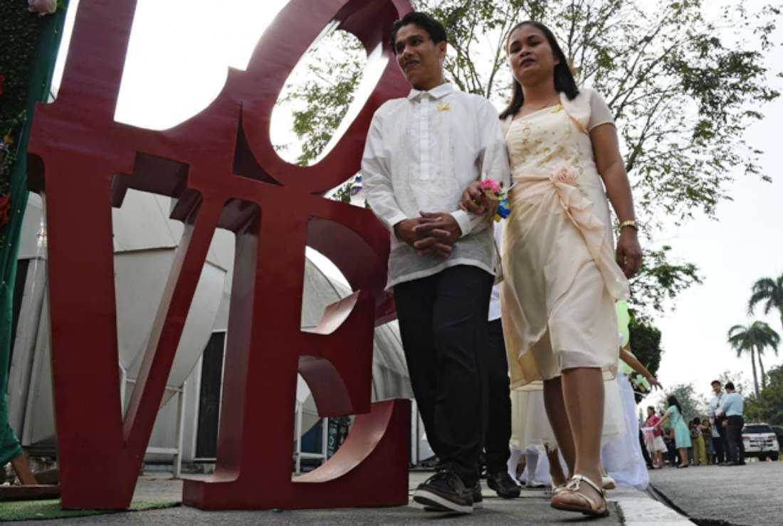 A couple march past a ‘LOVE’ decoration during a mass wedding as part of Valentine's Day celebrations in Philippine capital Manila on Feb. 14, 2019