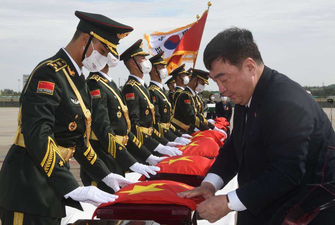 Chinese Ambassador to South Korea Xing Haiming (right) covers caskets containing the remains of Chinese soldiers with a Chinese national flag during the handing over ceremony at the Incheon International Airport in Incheon on Sept. 16, 2022