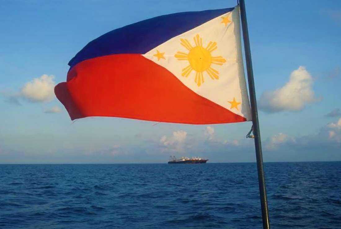This handout photo taken April 14, 2021, and received from the Philippine Coast Guard (PCG) April 15, a Philippine flag is displayed aboard a coast guard rubber boat as they patrol past Chinese vessels at Whitsun Reef, in the Spratly Islands. (Photo: Philippine coast Guard
