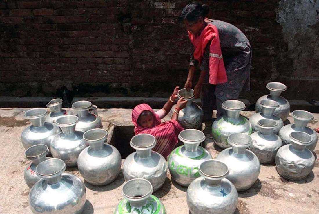 Two young Bangladeshi girls in old Dhaka's Nawabpur district fill jars with water from an underground supply on April 21, 2000. The worst water shortages are reported from the Barind region of northern Bangladesh where groundwater levels are reportedly fast decreasing