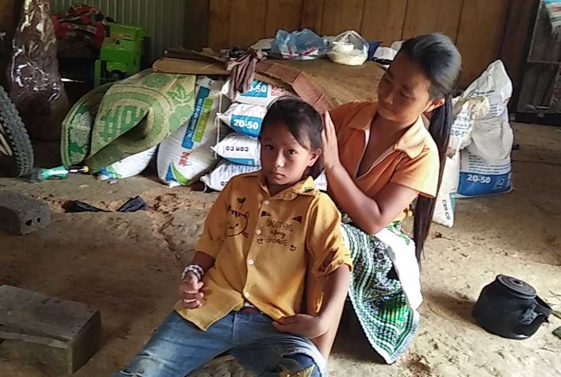 Teresa Vang Thi Cam combs her daughter’s hair in their house in Ban Lenh Subparish in Yen Bai province